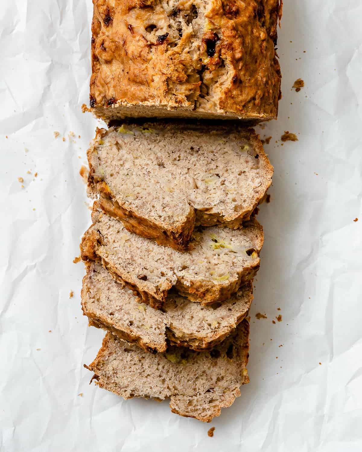 Einfaches Veganes Bananenbrot (Mit Apfelmus) 8 Fertiges, geschnittenes einfaches veganes Bananenbrot (mit Apfelmus) in einer Kastenform vor weißem Hintergrund