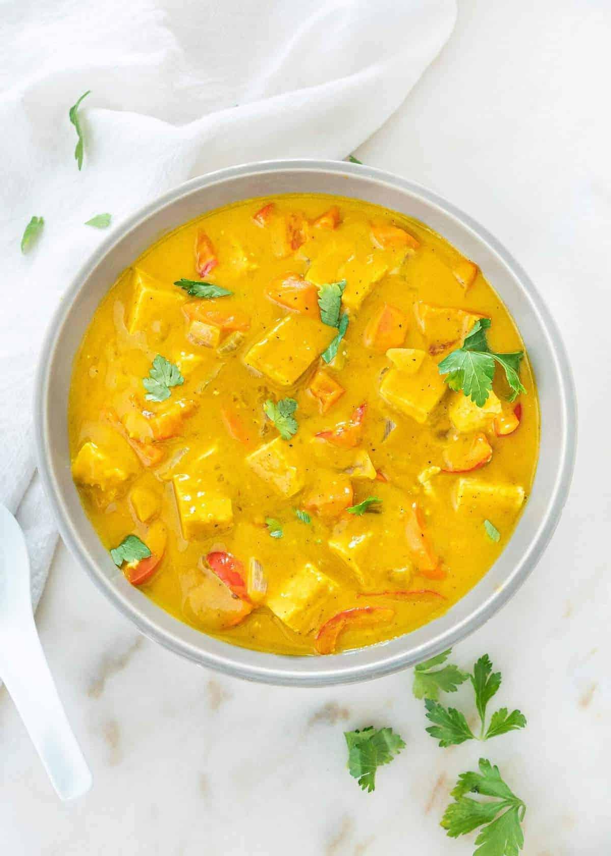 Kürbiscurry 8 Fertige Schale Kürbis-Curry auf weißem Marmoruntergrund