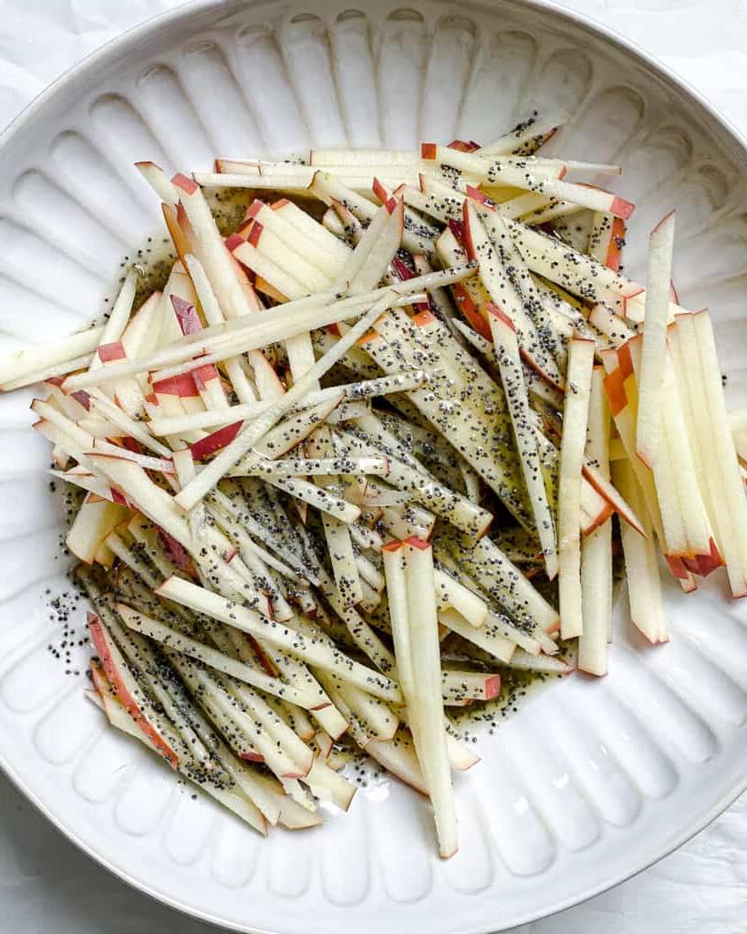 Gehobelter Rosenkohlsalat mit Äpfeln 8 Prozessaufnahme des Hinzufügens von Dressing zu Äpfeln