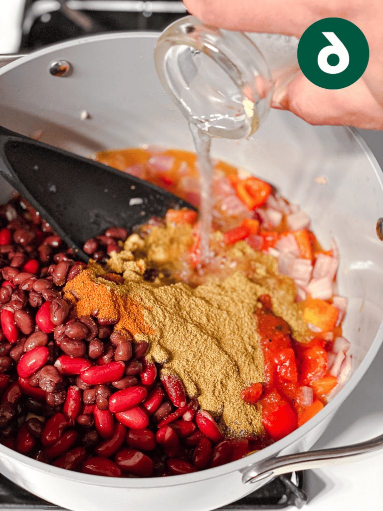 Veganes Kürbis-Chili für Schongarer und Herd 9 Prozessaufnahme des Hinzufügens von Wasser zur Pfanne