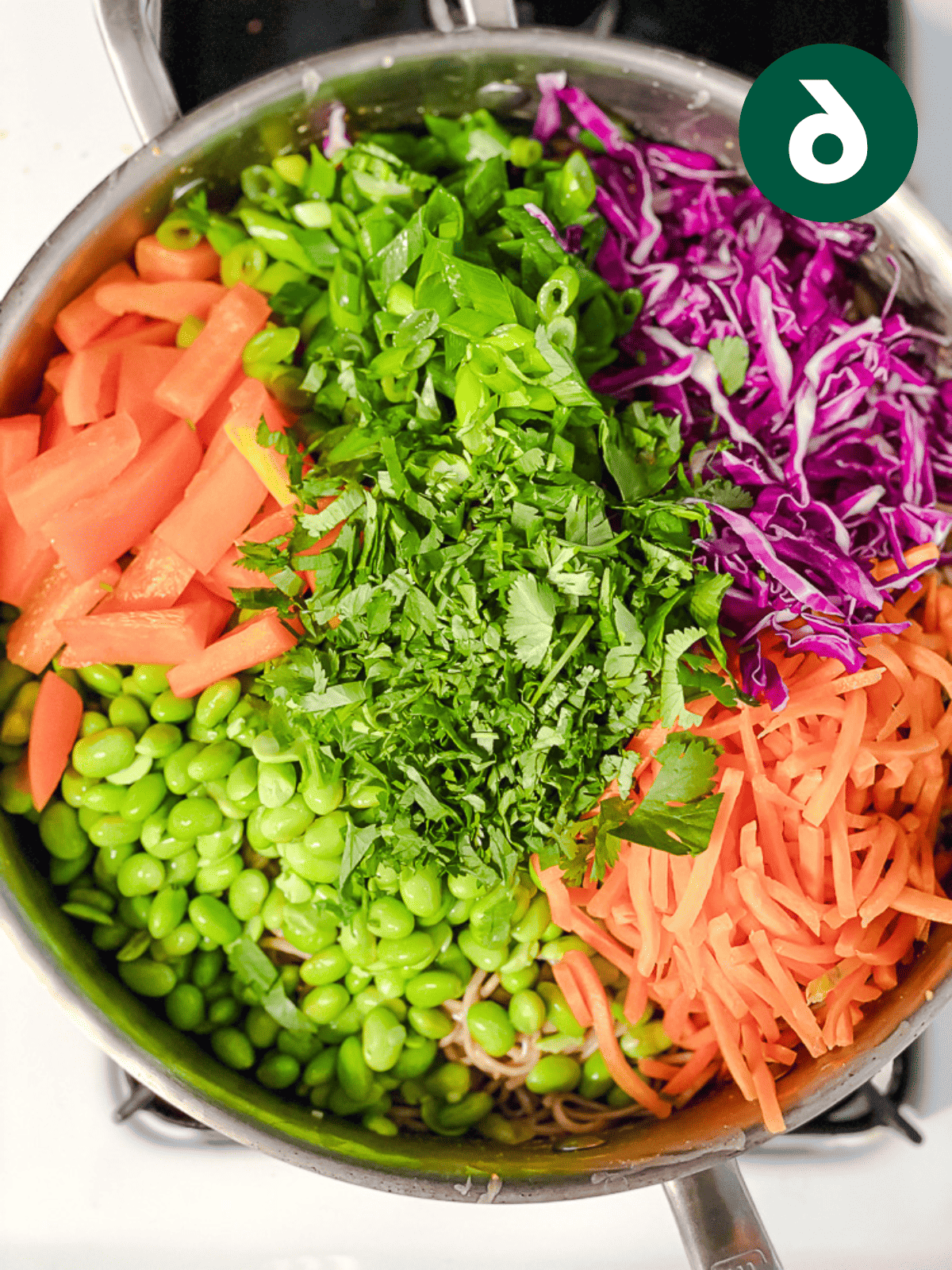 a medley of fresh vegetables on top of soba noodles in a large pot.