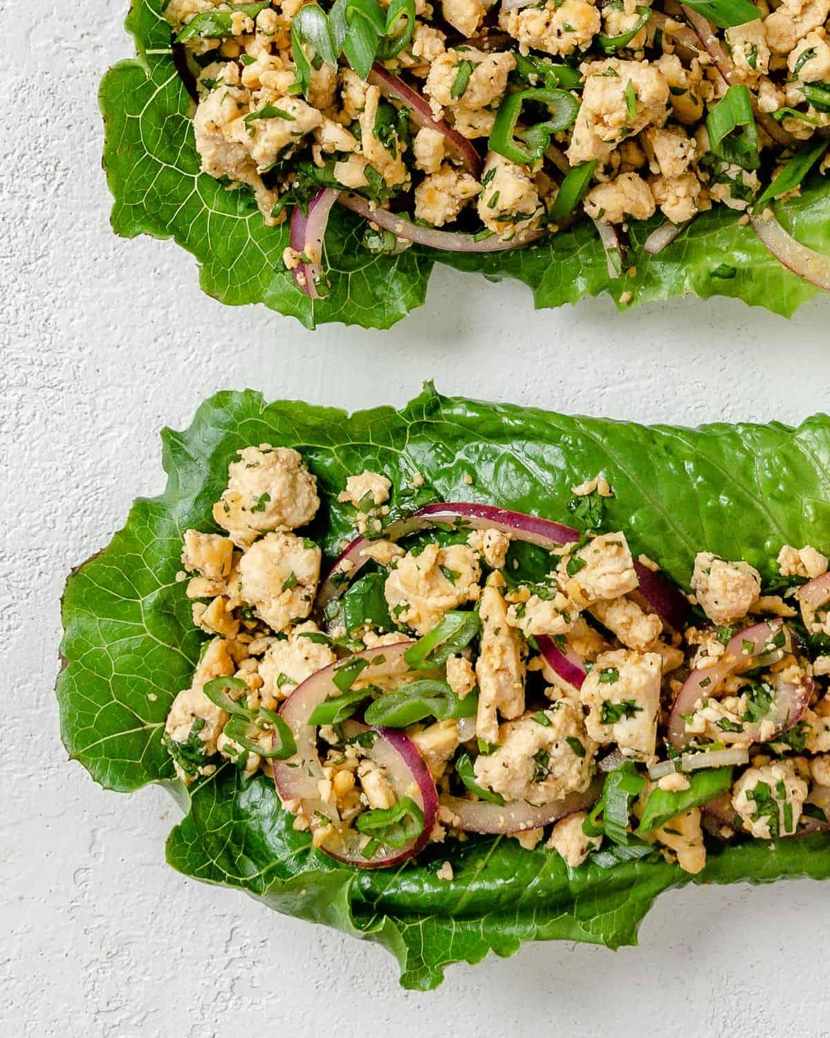 Veganer Tofu-Larb-Salat 9 Zwei fertige Larb Salatstücke auf weißem Hintergrund.