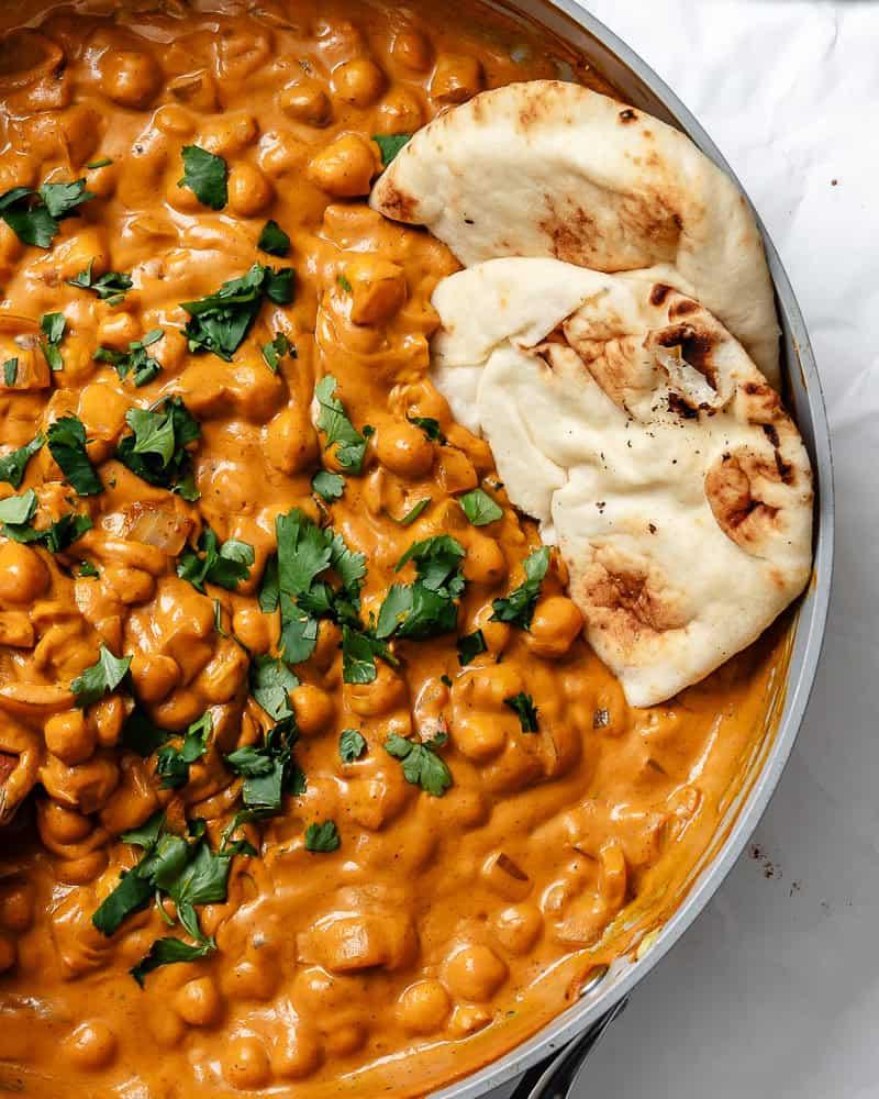 Curry-Kichererbsen 9 Fertiges Kichererbsen-Curry in einer großen Schüssel mit veganem Naan-Brot daneben.