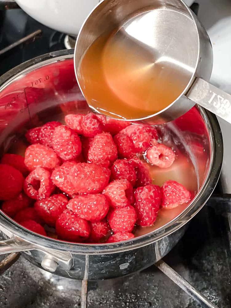 Peach Melba 9 Zuckersirup wird in einen Topf mit Himbeeren gegossen.