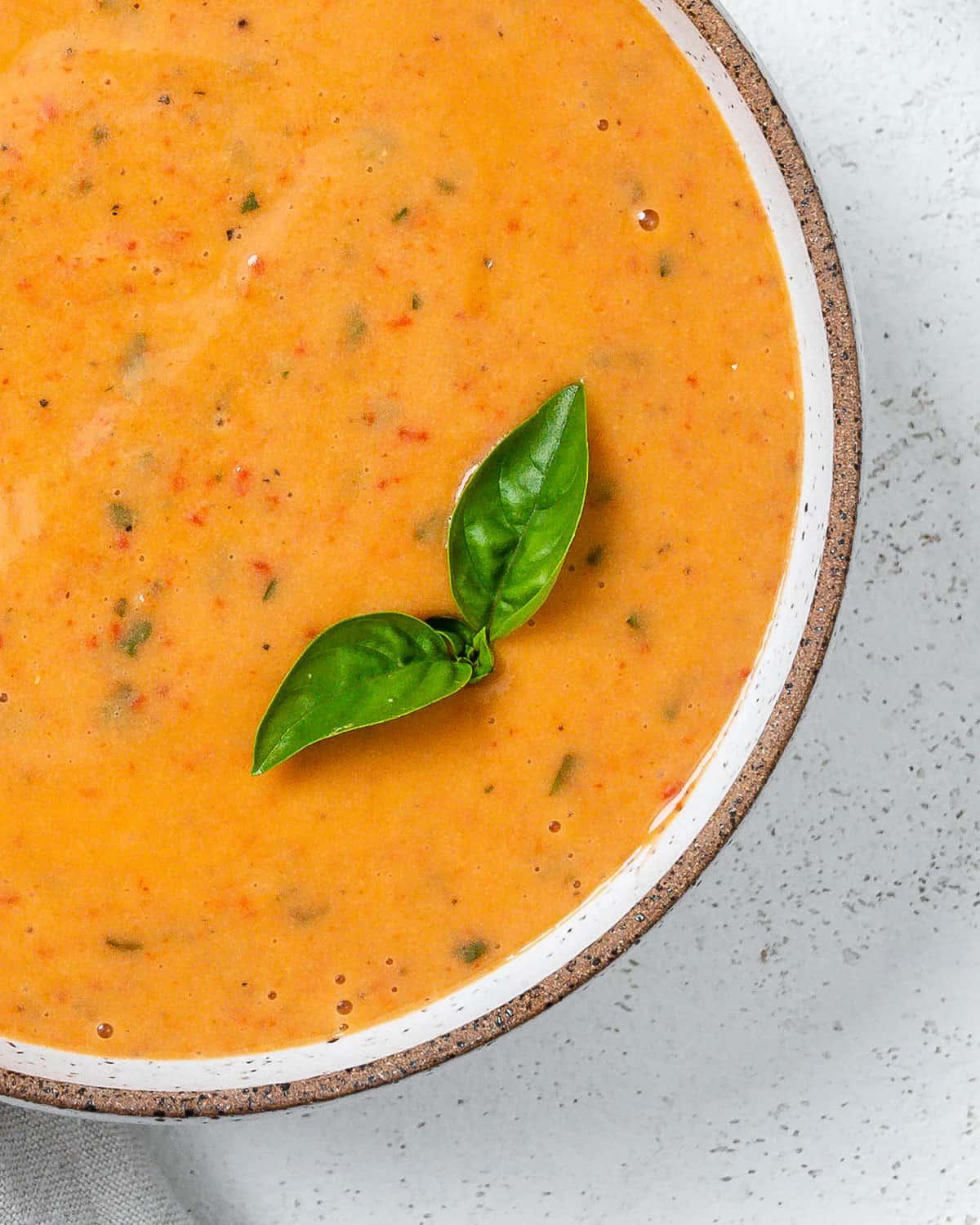 Cremige geröstete rote Paprikasuppe 9 Fertige cremige geröstete rote Paprika Suppe in einer Schüssel auf hellem Untergrund