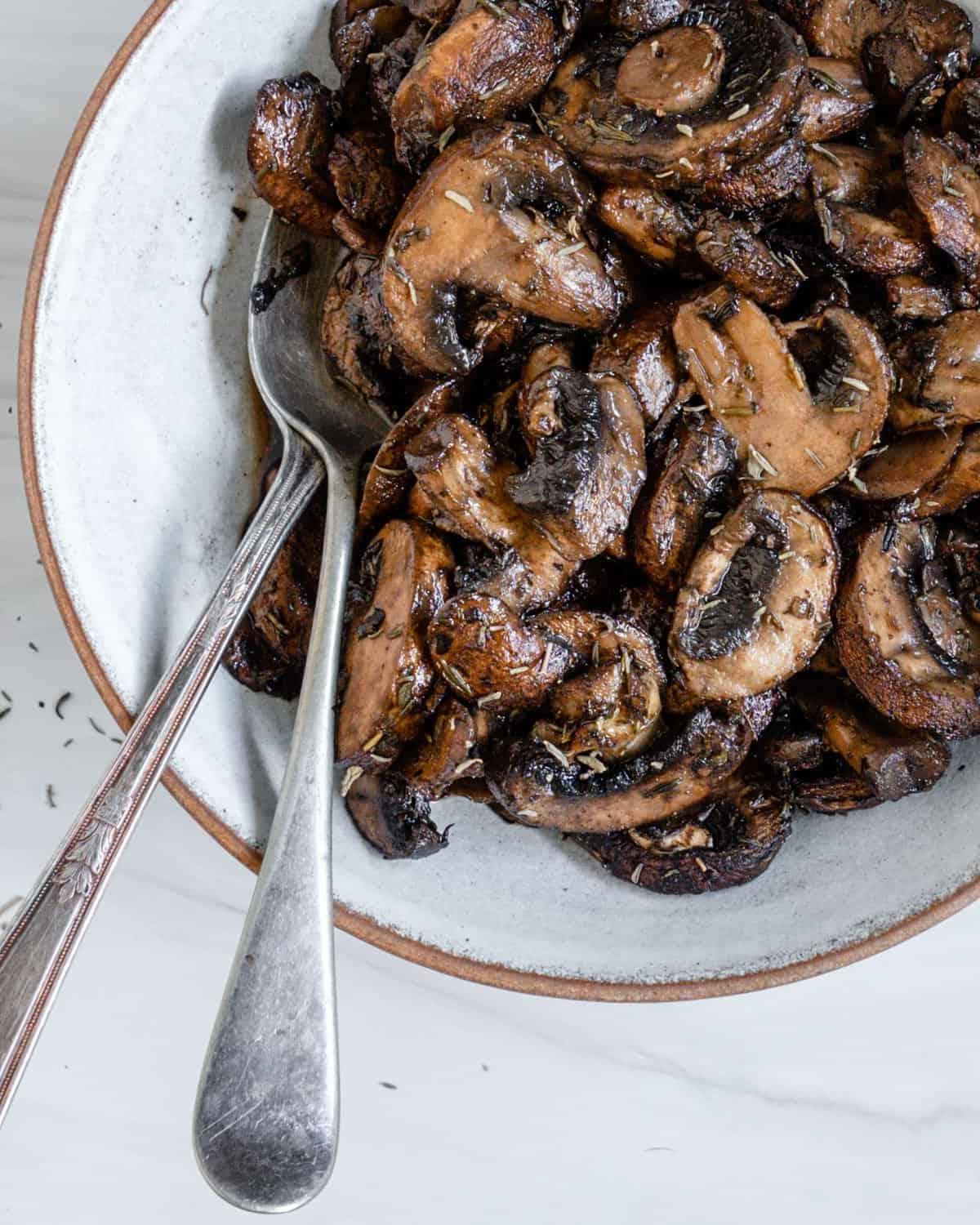 completed simple roasted mushrooms on a white plate against a white background