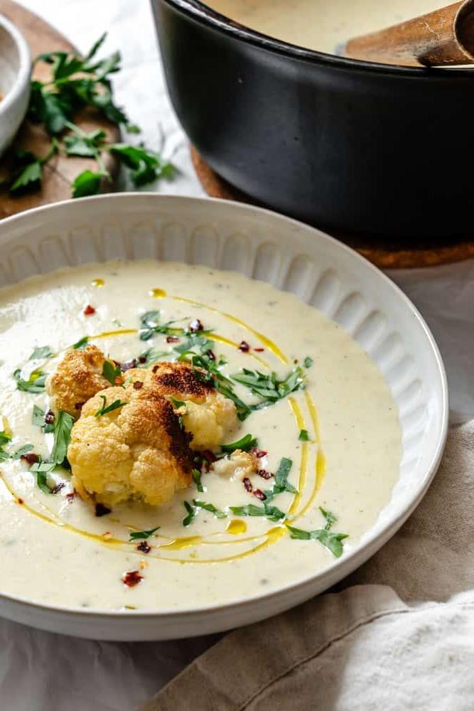 Geröstete Blumenkohlsuppe 9 Fertige Geröstete Blumenkohlsuppe in einer Schüssel mit frischen Kräutern garniert.