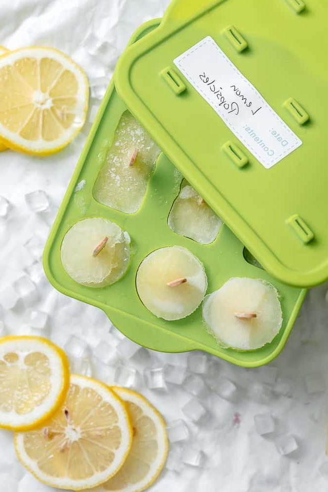 Fertige einfache Zitronen-Eis am Stiel in Formen auf weißer Oberfläche.