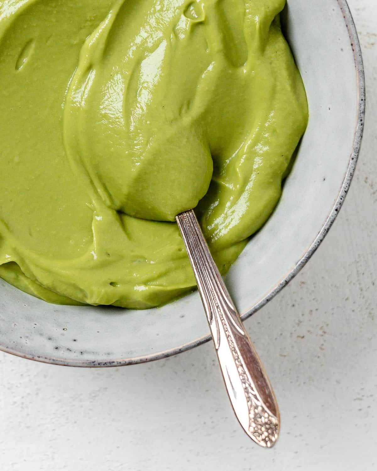 Einfacher Avocado-Aufstrich 9 Fertiger cremiger Avocado-Aufstrich in einer Schale vor hellem Hintergrund