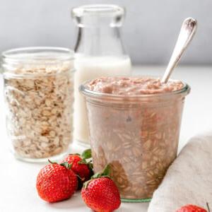 Erdbeer-Overnight-Oats (Vegan) 9 Fertige vegane Erdbeer Overnight Oats in zwei Gläsern mit Erdbeeren im Vordergrund auf einer weißen Oberfläche