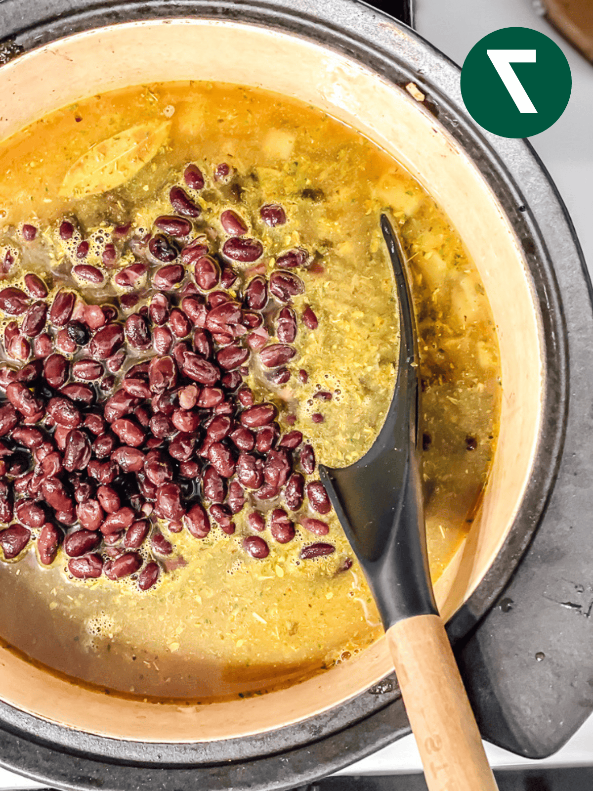 Schwarze Bohnensuppe 10 Ein großer schwarzer Löffel rührt schwarze Bohnensuppe in einem großen Topf.