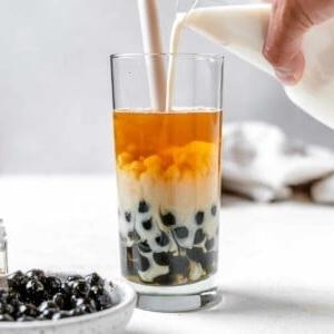 Einfacher Veganer Bubble Tea 10 process shot of pouring boba tea into a glass with ingredients in the background