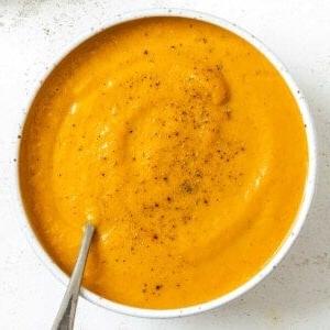 Cremige Curry-Karotten-Ingwer-Suppe 10 Fertige cremige Curry-Karotten-Ingwer-Suppe in einer weißen Schüssel auf weißem Hintergrund