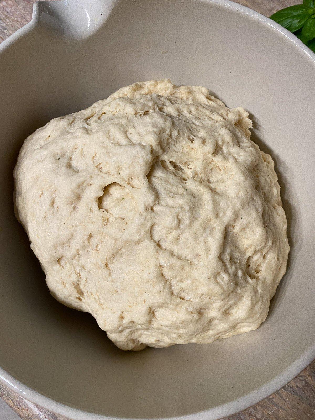 Vegane Pizzaröllchen 9 process of forming flour in a white bowl against a light brown surface