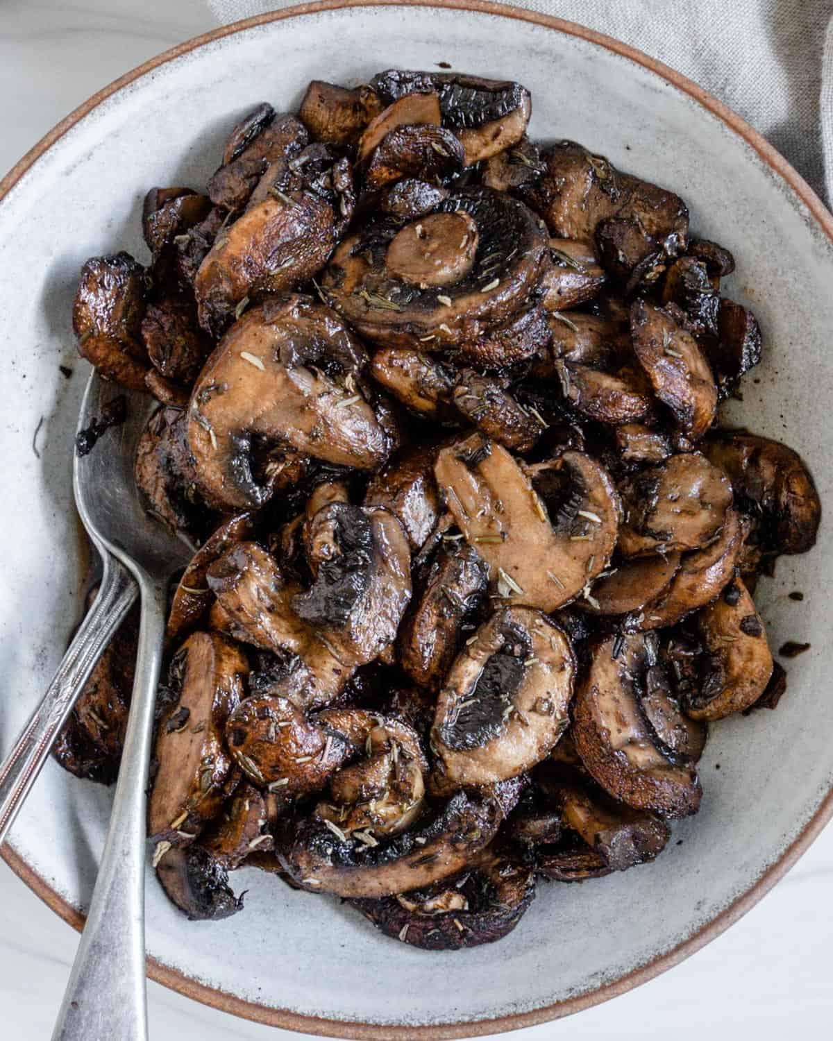 completed simple roasted mushrooms on a white plate against a white background