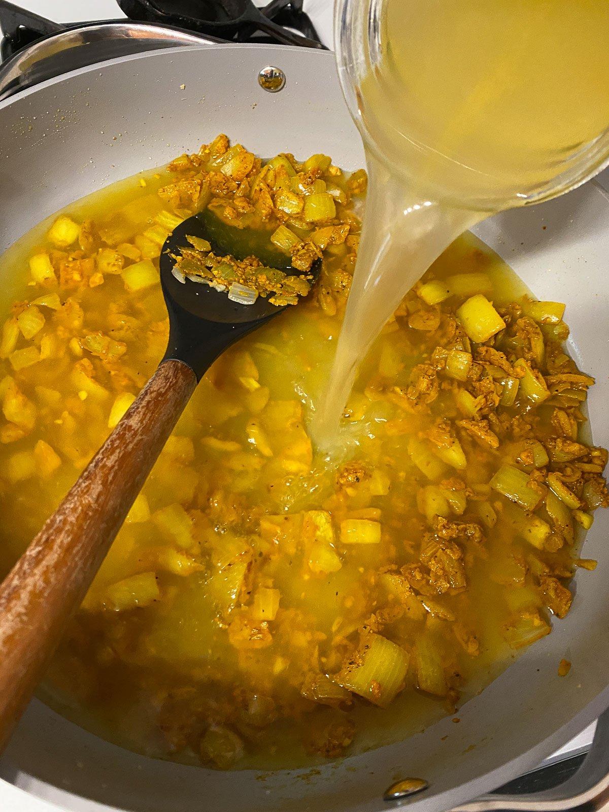 Einfaches gelbes Dal-Rezept 10 Gemüsebrühe in die Pfanne gegeben