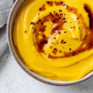 Fertiggestellte einfache vegane Kürbissuppe auf weißem Untergrund