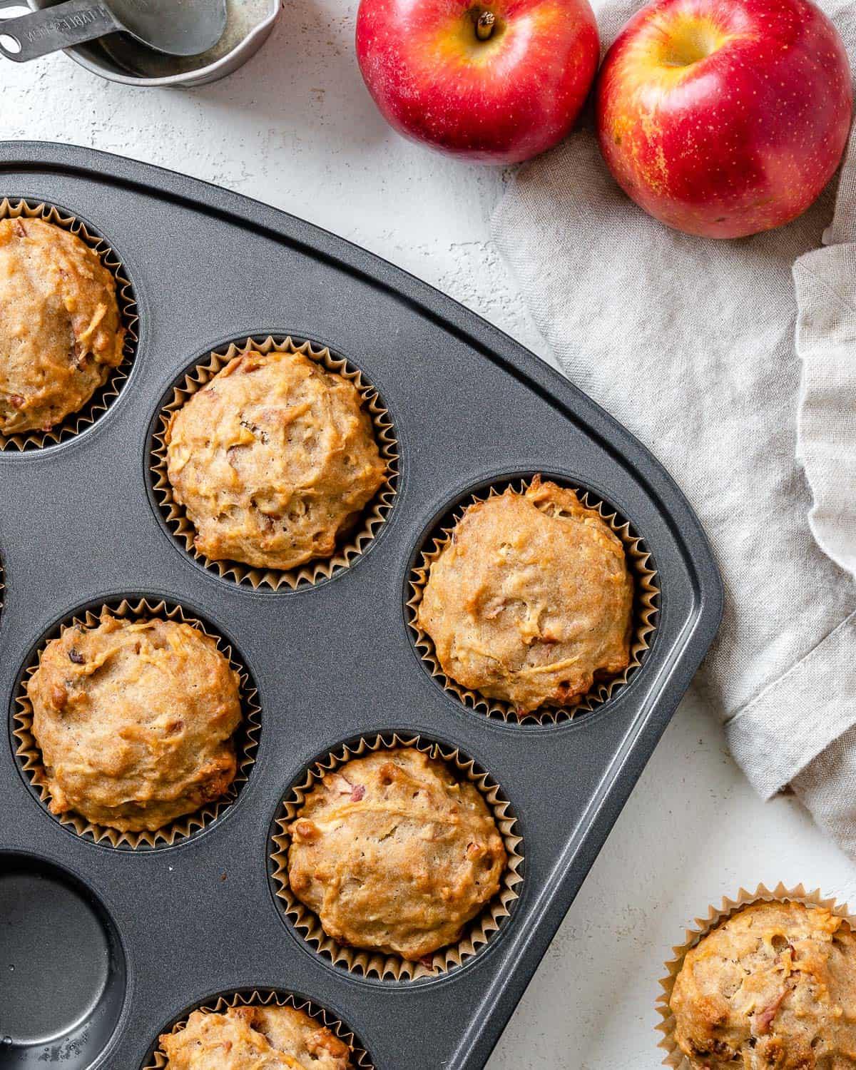 Einfache Vegane Apfelmuffins 10 Mehrere fertig gebackene vegane Apfelmuffins auf einer weißen Oberfläche ausgebreitet