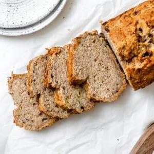Einfaches Veganes Bananenbrot (Mit Apfelmus) 10 Fertiges, geschnittenes einfaches veganes Bananenbrot (mit Apfelmus) in einer Kastenform vor weißem Hintergrund