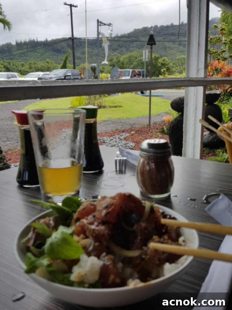 The Dolphin Restaurant in Hanalei, with lush green mountains and waterfalls in the background.