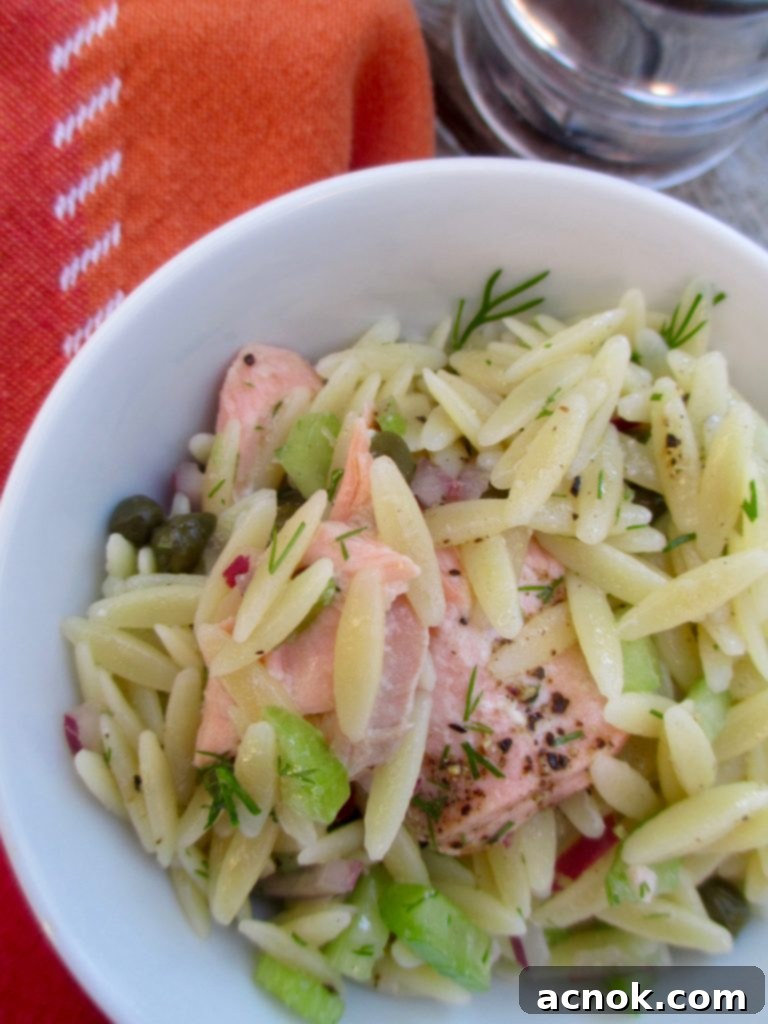 A bowl of freshly prepared Salmon Caper Orzo Salad, garnished with fresh dill.