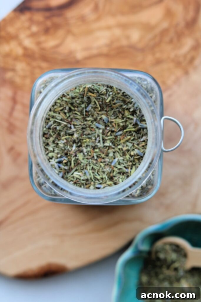 A rustic wooden spoon filled with Herbes de Provence blend on a textured surface.