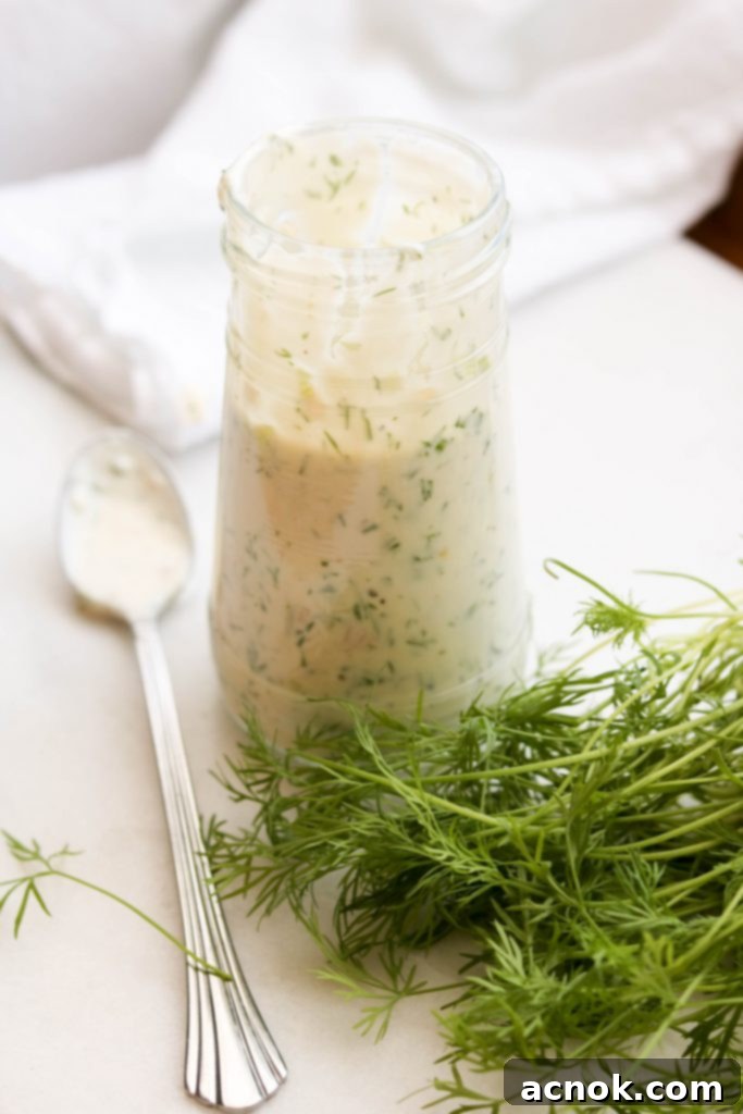 yogurt dill dressing in jar with spoon with fresh dill 
