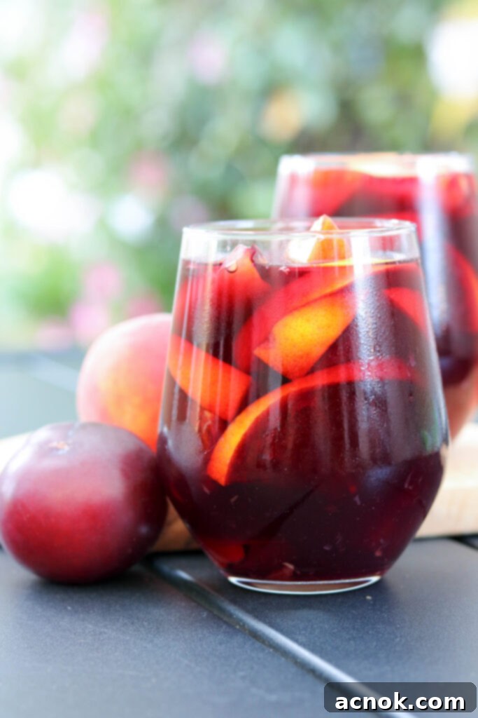 A glass of sangria on a rustic wooden table, with a pitcher in the background, showcasing the refreshing drink.