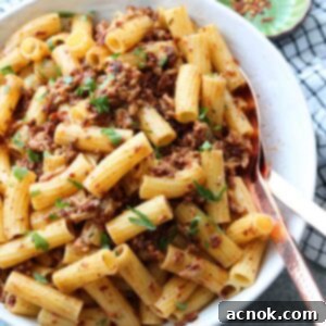 pasta with chicken sun dried tomatoes and garlic in serving bowl with utensils