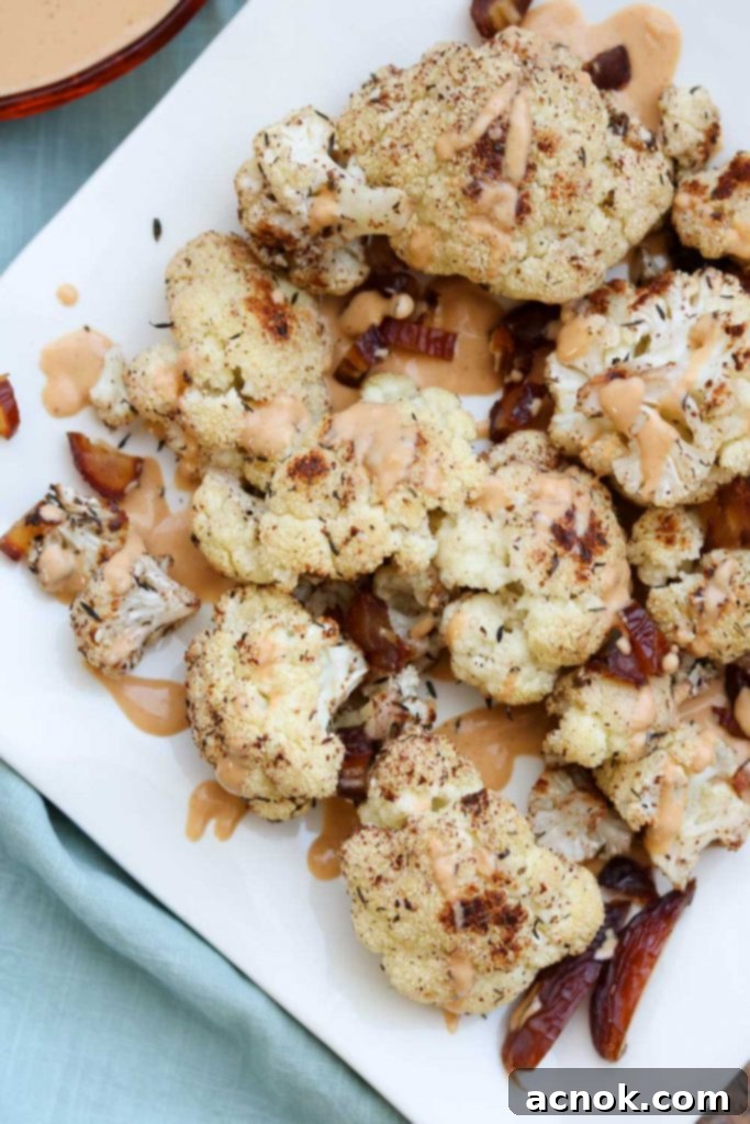 Roasted Cauliflower on plate, drizzled with Golden Tahini Harissa Sauce and sprinkled with chopped Medjool dates