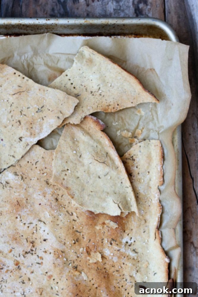 Large, golden-brown cracker sheet on a baking pan, ready to be broken into rustic pieces.