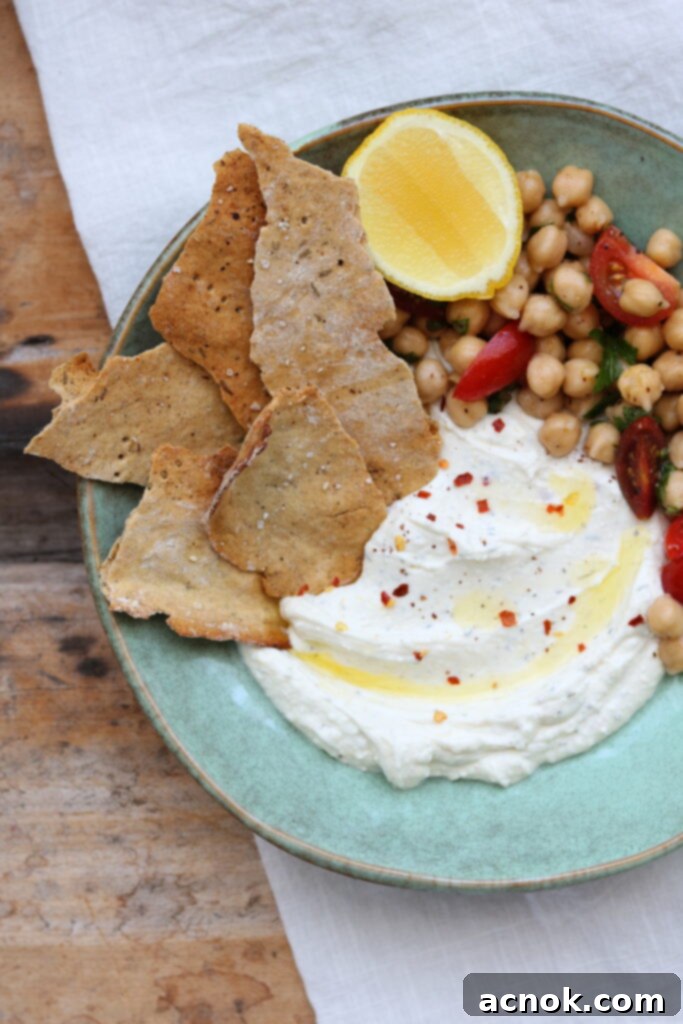 Creamy whipped feta and yogurt dip garnished with fresh herbs, perfect for dipping crackers.