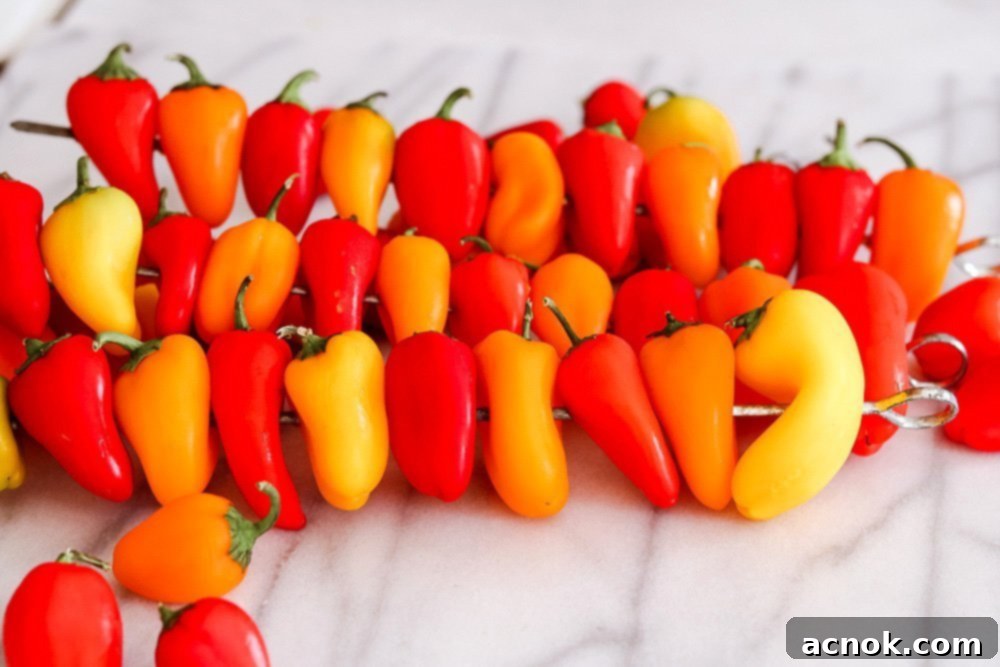 Skewered colorful baby bell peppers on a grill, charring nicely.
