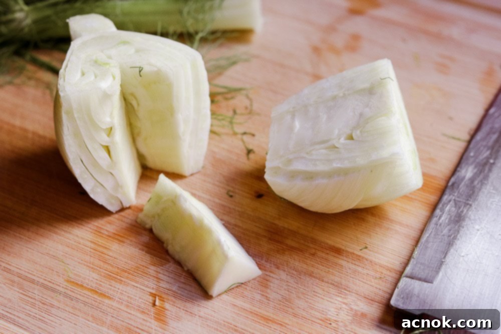 Hands demonstrating how to remove the core from a fennel bulb for salad preparation.