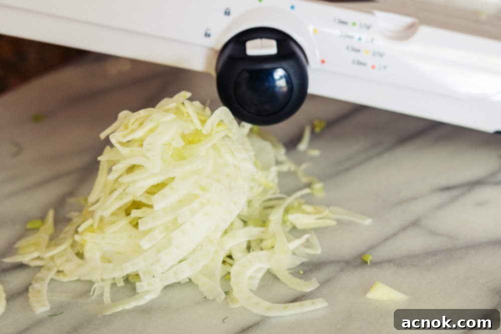 Thinly sliced fennel, showing delicate, almost translucent pieces, prepared with a mandoline or sharp knife.