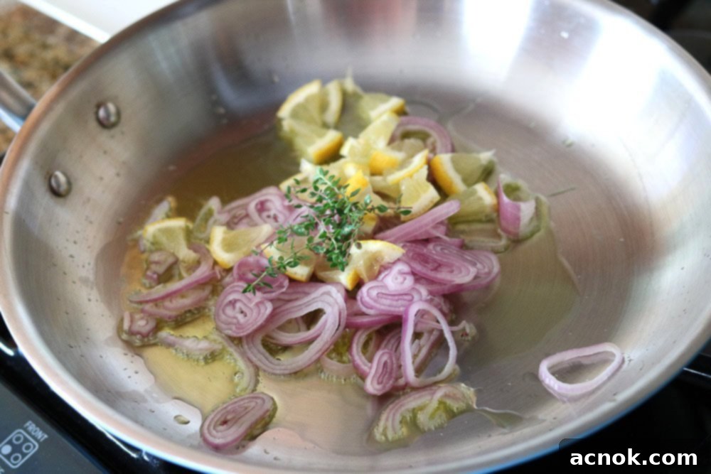 Thinly sliced shallots, lemon pieces, and thyme sprigs being added to warm olive oil in a pan.