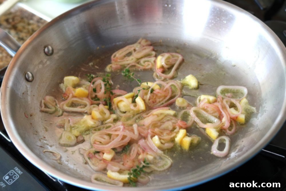 Shallots, lemon, and thyme gently sautéing in a pan, seasoned with salt and pepper.