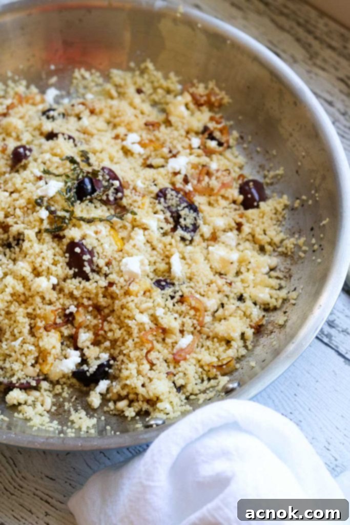 Lemon Thyme Couscous in a pan, fully mixed and fluffy, garnished with fresh herbs.