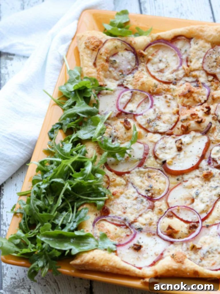 Savory puff pastry with pears, gorgonzola, and walnuts on a platter with arugula, ready to serve.