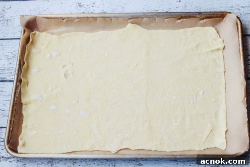 Puff pastry dough rolled out on a parchment-lined baking sheet, showing preparation for toppings.