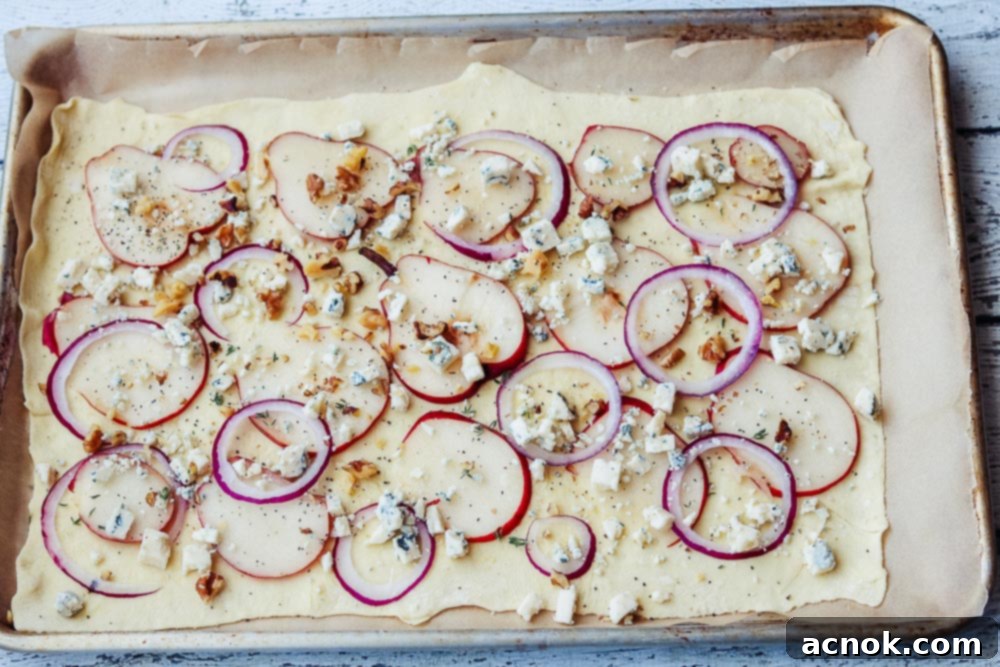 Puff pastry tart with pears, gorgonzola, and walnuts ready for baking, showing toppings arranged.