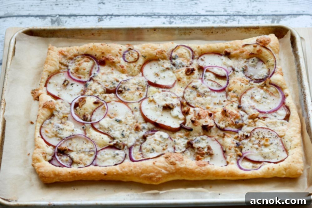 Freshly baked puff pastry tart, golden and puffed, cooling on a rack, showcasing the cooked toppings.