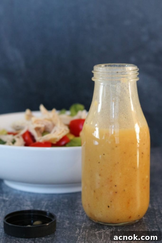 White Balsamic Honey Mustard Vinaigrette in a bottle with a fresh green salad in the background