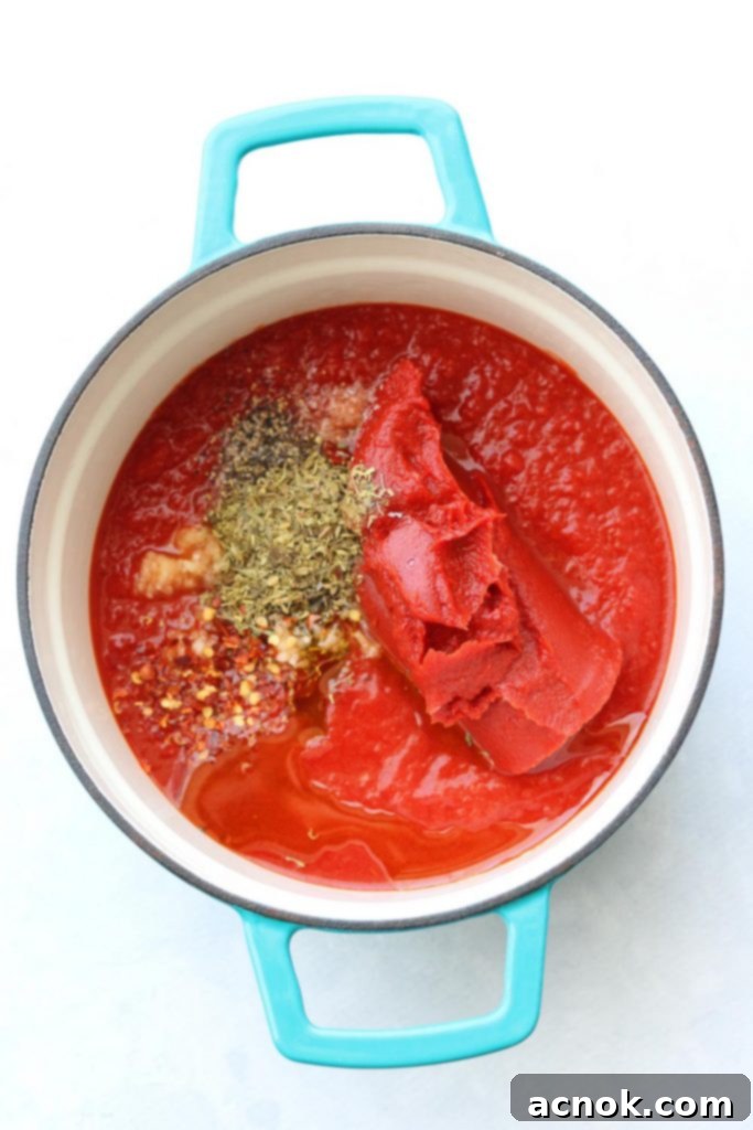 Fresh ingredients for Rich and Zesty Pizza Sauce, including crushed tomatoes, tomato paste, garlic, and Italian seasoning.