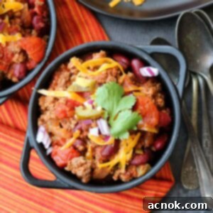 A single serving of Fast and Easy Beef Chili, topped with cheese and a spoon ready to dive in