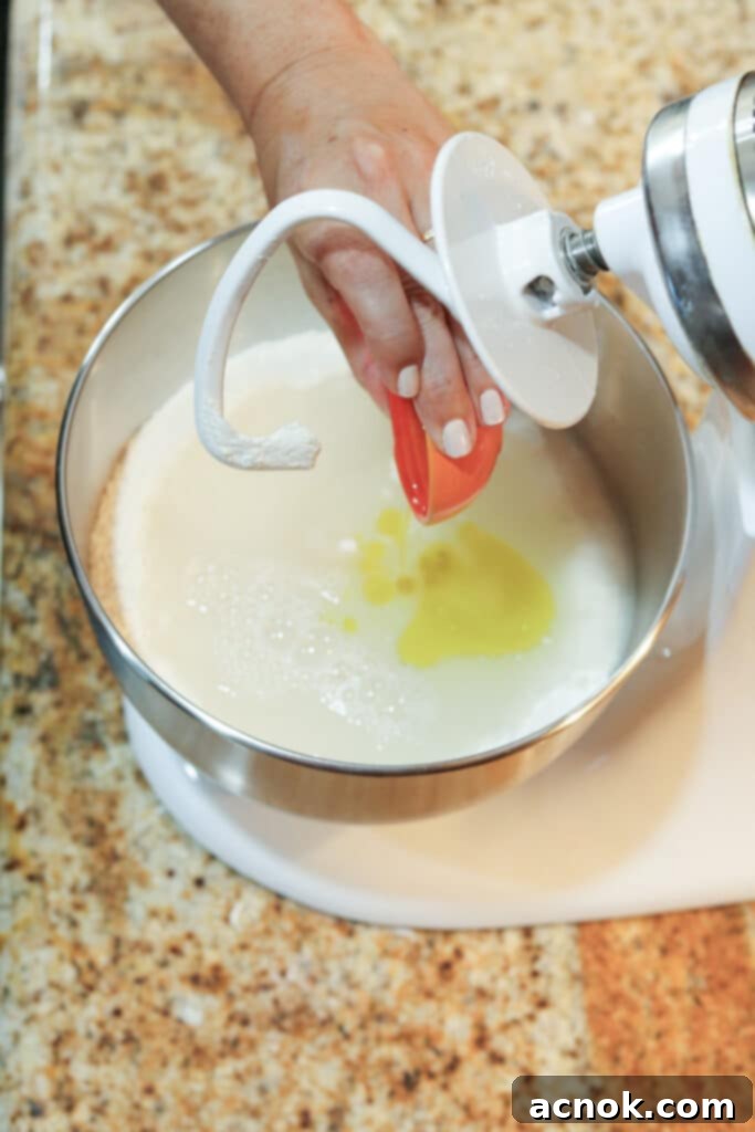 adding wet ingredients to the stand mixer for pizza dough