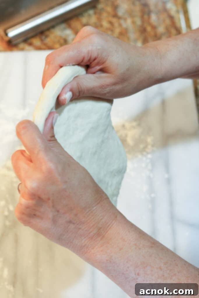 lifting and stretching pizza dough using gravity to form a circle