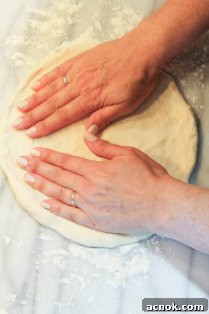 continuing to rotate and stretch pizza dough on a floured surface