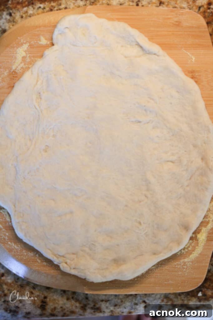 stretched pizza dough placed on a cornmeal-dusted pizza peel