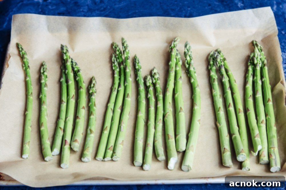 fresh asparagus spears arranged on a rimmed baking sheet